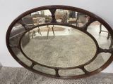un grand miroir ovale posé à même le sol dans un salon