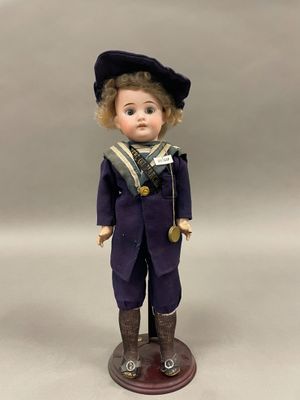 une figurine représentant un garçon vêtu d'un costume de marin et d'une casquette
