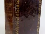 an old book sitting on top of a white table next to a white wall