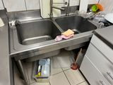 un évier en acier inoxydable dans une cuisine, à côté d'une cuisinière