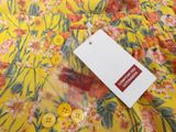 a tag on a yellow floral shirt with buttons on it