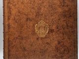 an old brown leather book with a gold emblem on the cover
