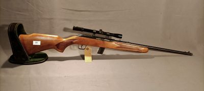 a rifle with a scope and a rifle stand on a white background