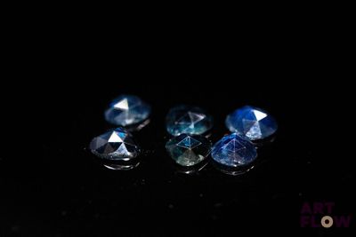 four blue sapphires on a black surface in the dark