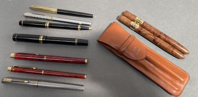 many pens and a pen case sitting on a table