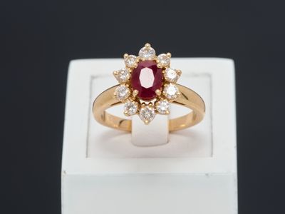 a close up of a gold ring with a ruby and diamond center