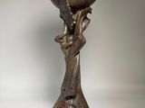 bronze sculpture of a woman holding a bowl on a pedestal