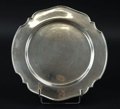 une assiette en argent posée sur un socle, sur un fond noir