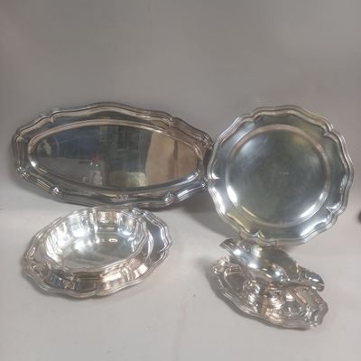 trois plats en métal argenté et un miroir posés sur une table