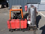 a red tank sitting on a pallet with a machine attached to it