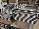 Plusieurs casseroles en acier inoxydable sont empilées sur une étagère dans une cuisine