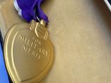 un ruban violet dans un écrin surmonté d'une médaille d'or