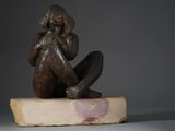 statue of a woman sitting on a rock with her hands on her face