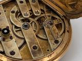 a close up of a pocket watch on a white surface