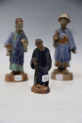 three figurines of a man and a woman on a white surface