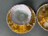 two gold and white plates with a pink flower on them
