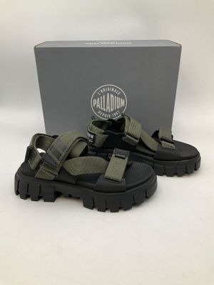 une photo d'une paire de sandales noires et vertes posées devant une boîte