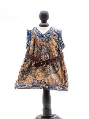 une robe posée sur un pied de mannequin, avec une ceinture autour