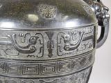 a large metal vase with a handle on a table