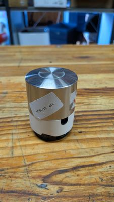 une enceinte argentée posée sur une table en bois