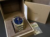 Une montre Michael Korsch dans une boîte, à côté d'une autre boîte contenant une montre