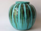 a blue vase with green stripes on it on a white surface