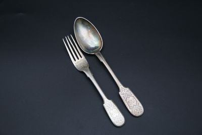 deux cuillères et une fourchette en argent sur une surface noire