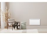 a white electric radiator sitting in a room next to a chair