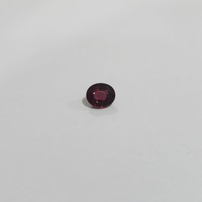 a red garnet stone on a white surface