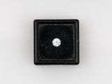 un gros plan d'un diamant dans un écrin noir posé sur une surface blanche