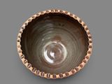 a brown bowl with dots on it on a gray surface