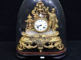 a gold clock under a glass dome on a black surface