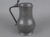 an antique pewware pitcher with a bird handle
