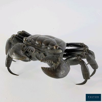 un crabe en métal posé sur une surface blanche