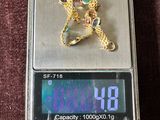 une balance numérique sur laquelle sont posés une horloge et un collier en or