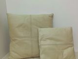 beige pillows on a bed in a room with a white wall