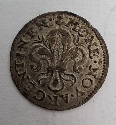 une vieille pièce de monnaie ornée d'une fleur, posée sur une surface blanche