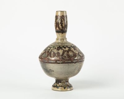 un petit vase posé sur une surface blanche