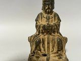 une vieille statue en bronze représentant un homme assis sur une chaise