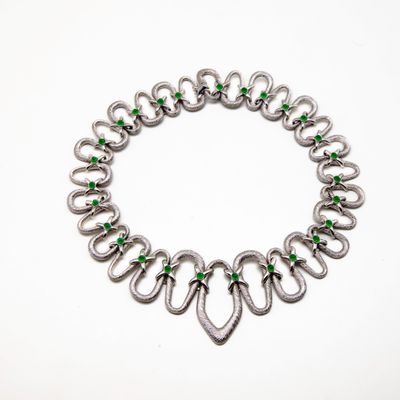 un gros plan sur un bracelet en argent orné de pierres vertes