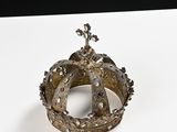 silver crown on a white surface with a cross in the middle