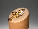 gold and garnett ring with garnets on top of a wooden box