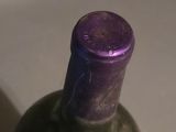 a bottle of wine sitting on a counter with a purple cap