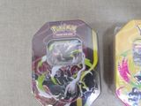 two tins of pokemon toys sitting on a table