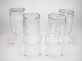 four clear plastic stools sitting next to each other on a white surface