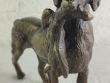 statue of a dog holding a bird in its mouth on a white surface