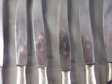 several knives are lined up on a table with a knife in front of them