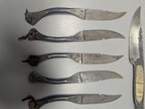 five knives and a knife sharper sitting on a white surface