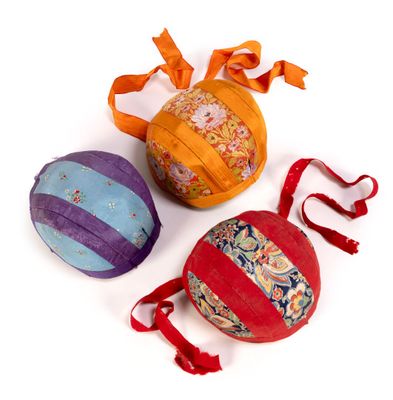three different colored balls with ribbons and bows on a white surface
