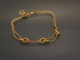 gros plan d'un bracelet en chaîne en or sur une surface noire